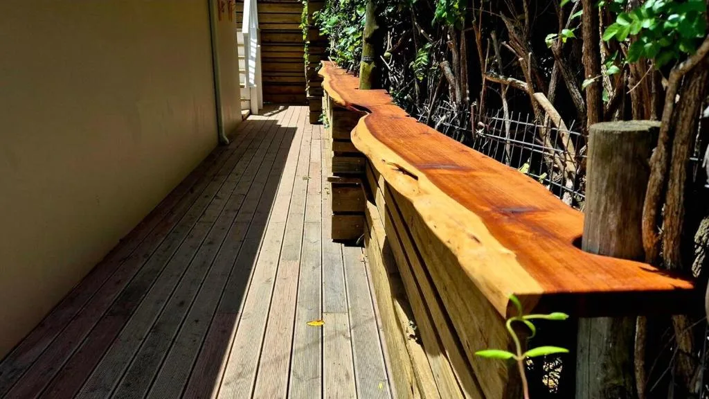Wooden deck with polished rail overlooking lush green garden vegetation