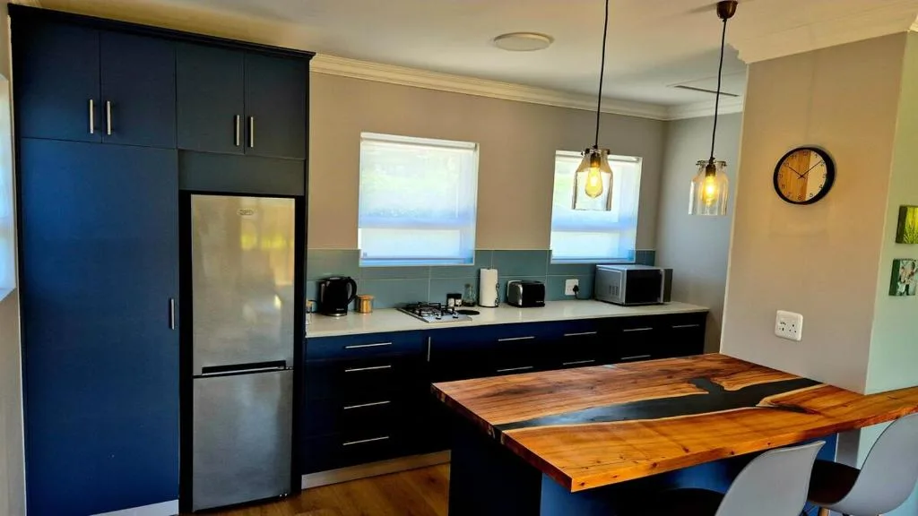 Modern kitchen with dark cabinetry, stainless steel appliances, and wooden dining table