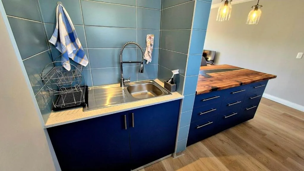 Modern kitchen with blue cabinetry, stainless steel sink, and wooden countertop