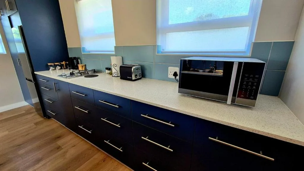 Modern kitchen with dark cabinetry, white countertop, and stainless steel appliances