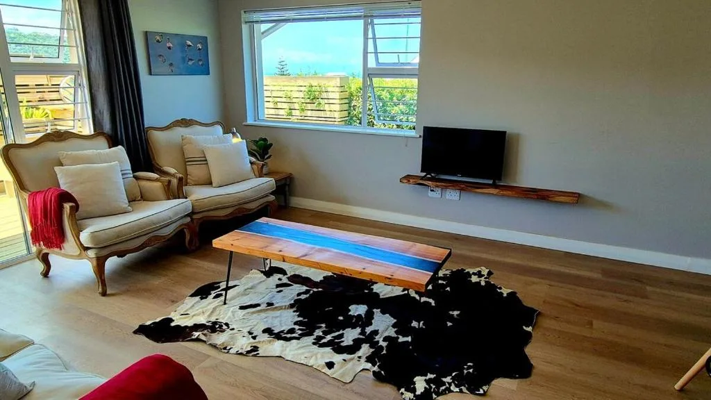 Bright living room with armchairs, TV, and scenic landscape views through windows