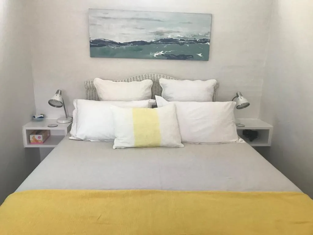 Neatly made bed with white pillows and yellow accent throw blanket