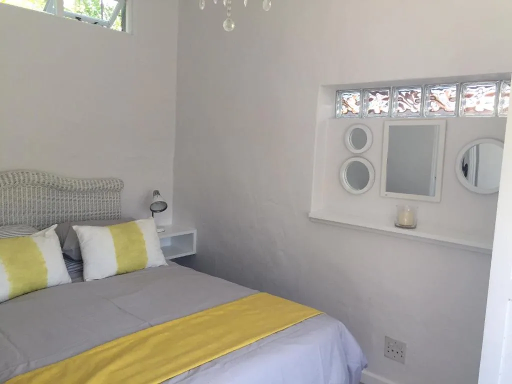 Bright bedroom with yellow and white bedding, wicker headboard, mirrors
