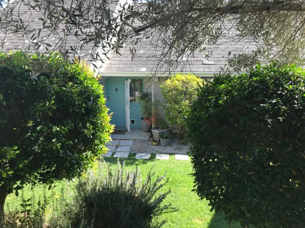 Charming cottage entrance with turquoise door surrounded by lush green garden