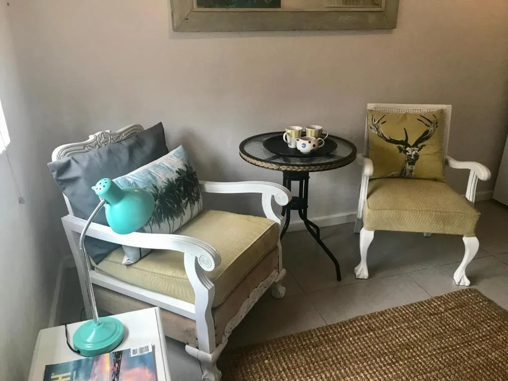 Stylish lounge corner with white-framed armchairs and black side table