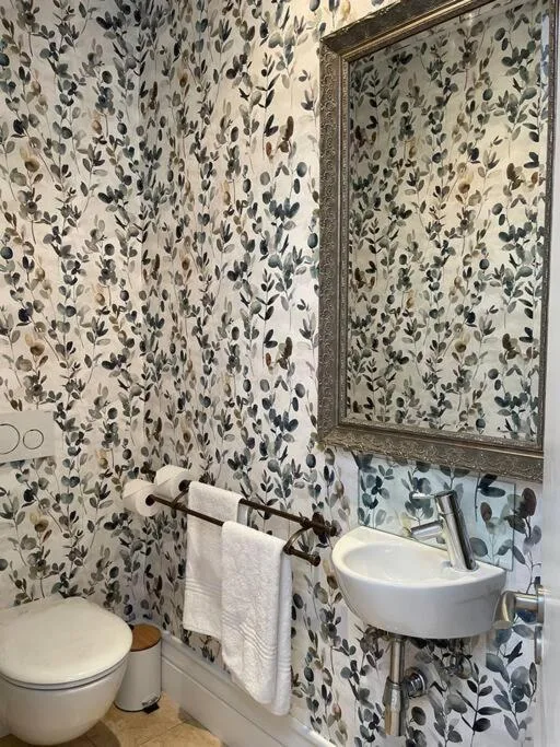 Modern bathroom with botanical wallpaper, white sink, and framed mirror