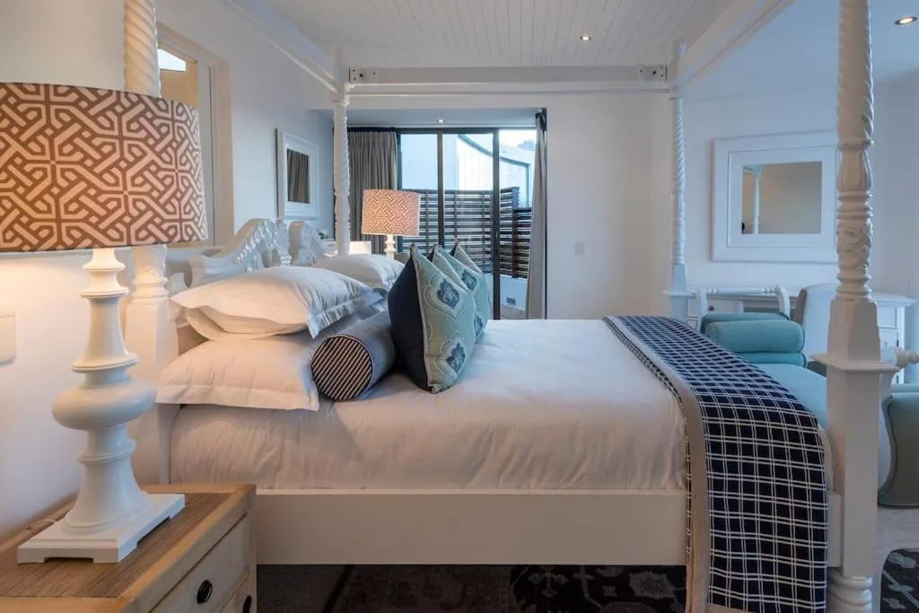 Bright master bedroom with king bed, coastal decor, and ocean view balcony doors
