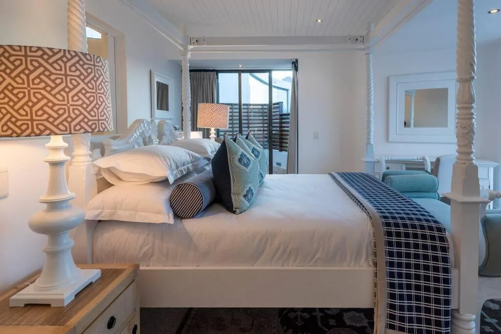 Spacious bedroom with queen bed, ocean view balcony, elegant white furnishings