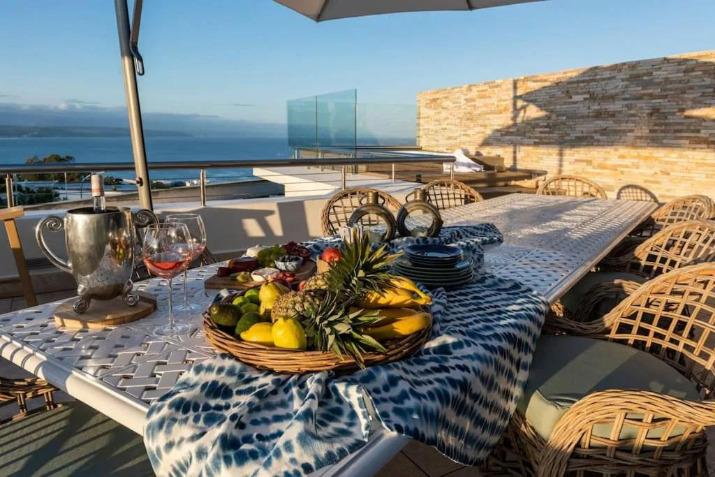 Outdoor dining table overlooking ocean with mountain views and fresh fruit