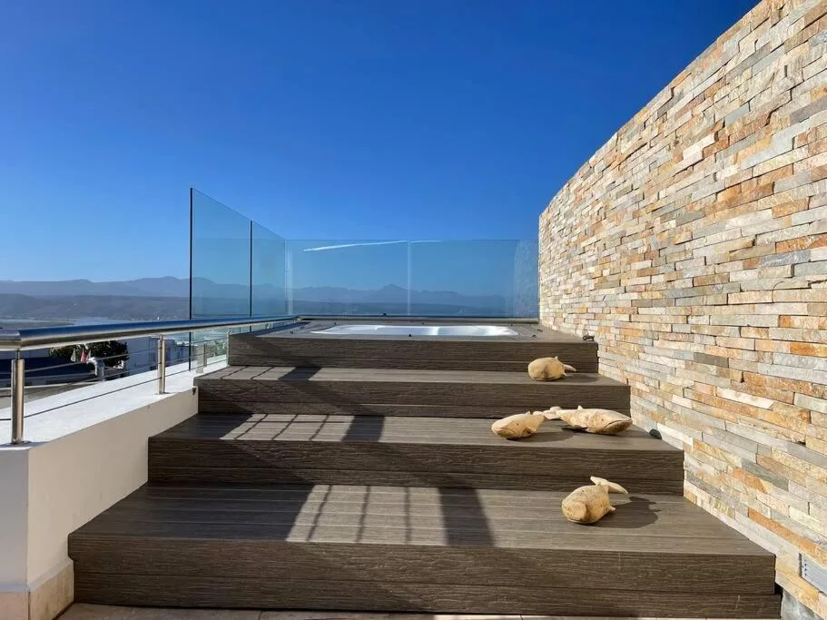 Wooden deck with glass railings overlooking mountain views and ocean
