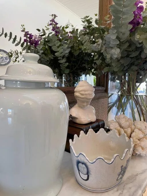 Decorative display with ceramic vessels, fresh flowers, and sculptural accents
