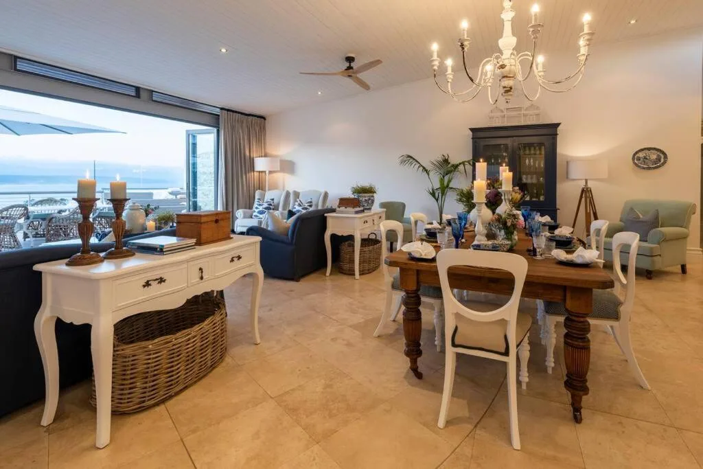 Elegant dining table with white chairs and ocean views through large windows