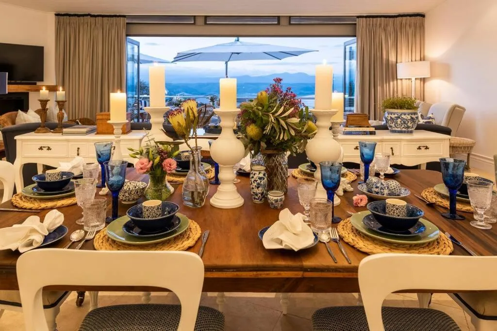 Elegantly set dining table overlooking ocean and mountains through expansive windows