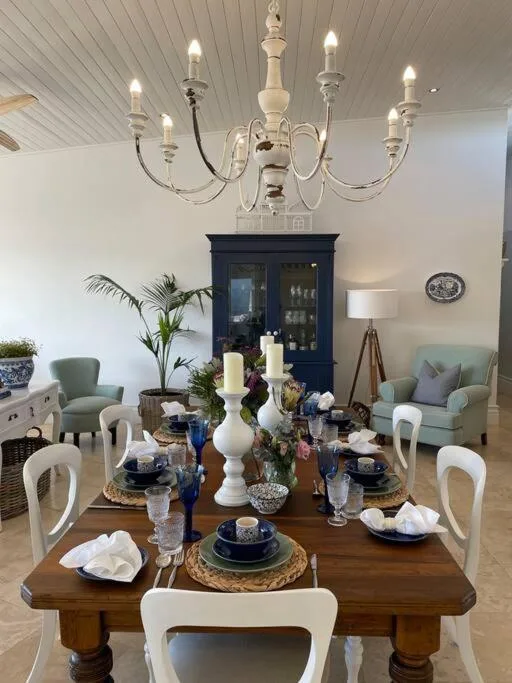 Elegantly set dining table with wooden top and white chairs, coastal decor