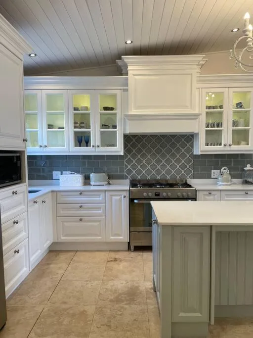 Modern kitchen with white cabinetry, stainless steel appliances, and geometric tile backsplash