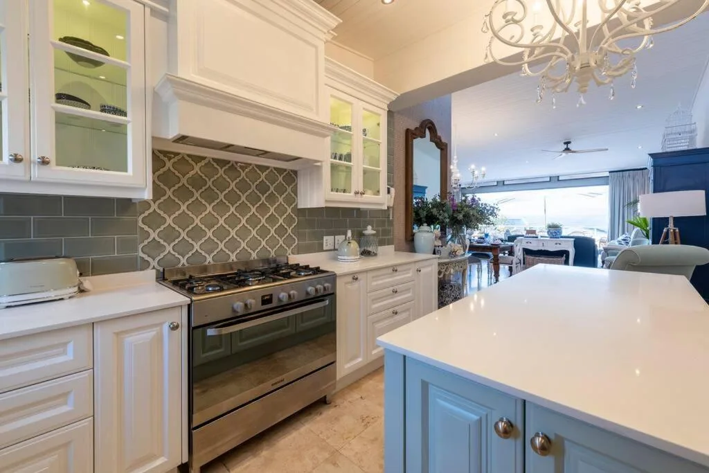 Modern kitchen with white cabinetry, gas stove, and ocean views beyond