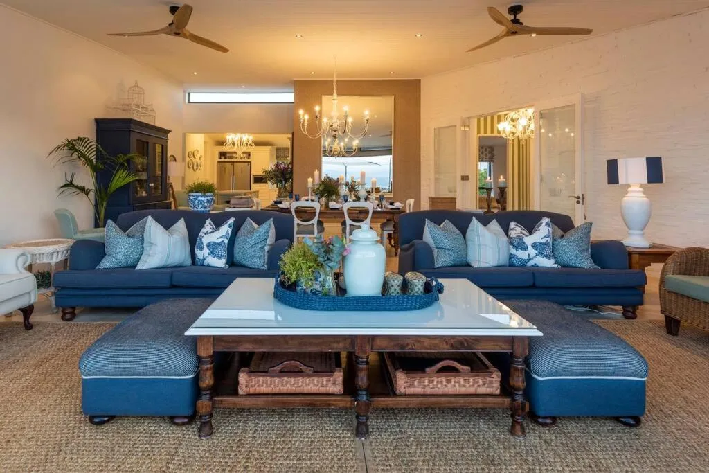 Elegant lounge with dual navy sofas, white coffee table, ocean view through large windows