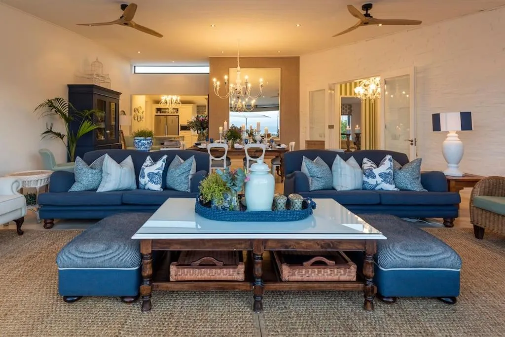 Spacious living room with dual navy sofas, white marble coffee table, and elegant chandelier