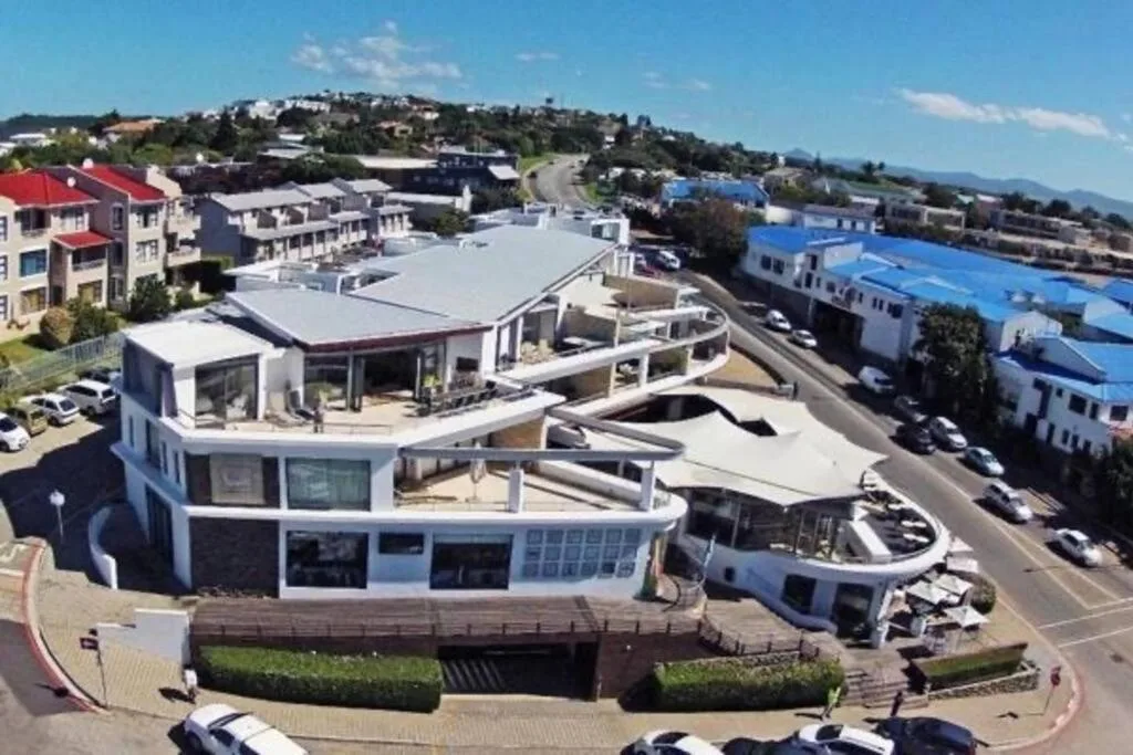 Aerial view of modern white building overlooking Plettenberg Bay town and mountains