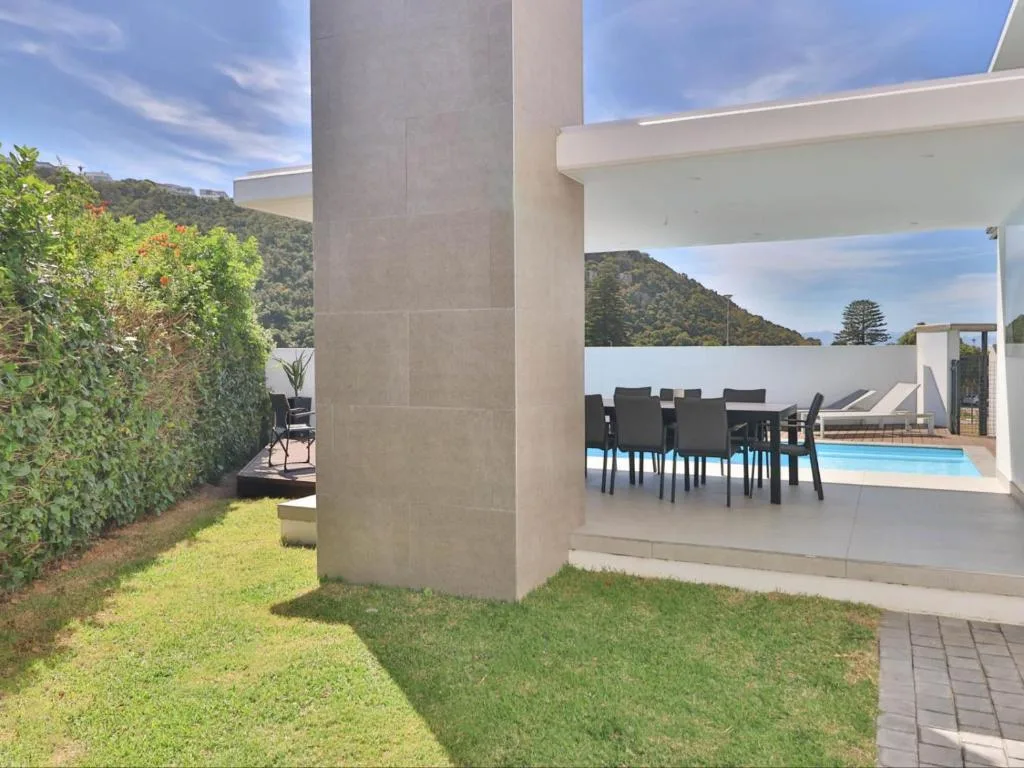 Modern patio with dining table overlooking swimming pool and gardens