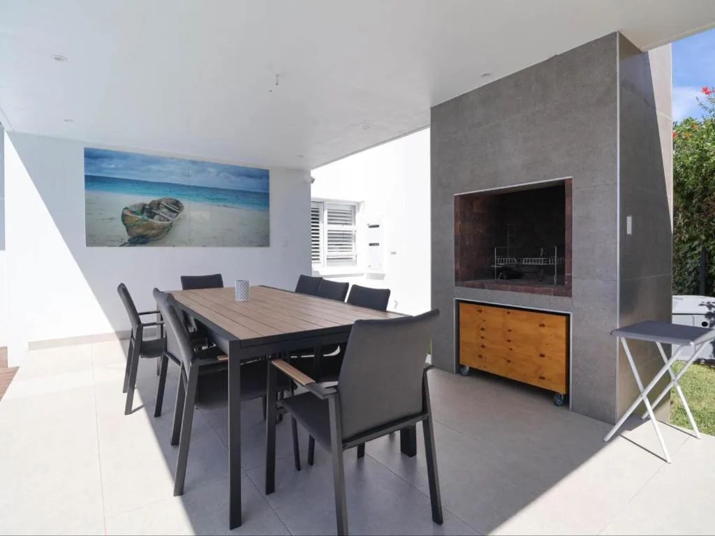 Modern dining area with wooden table and black chairs, ocean artwork on wall
