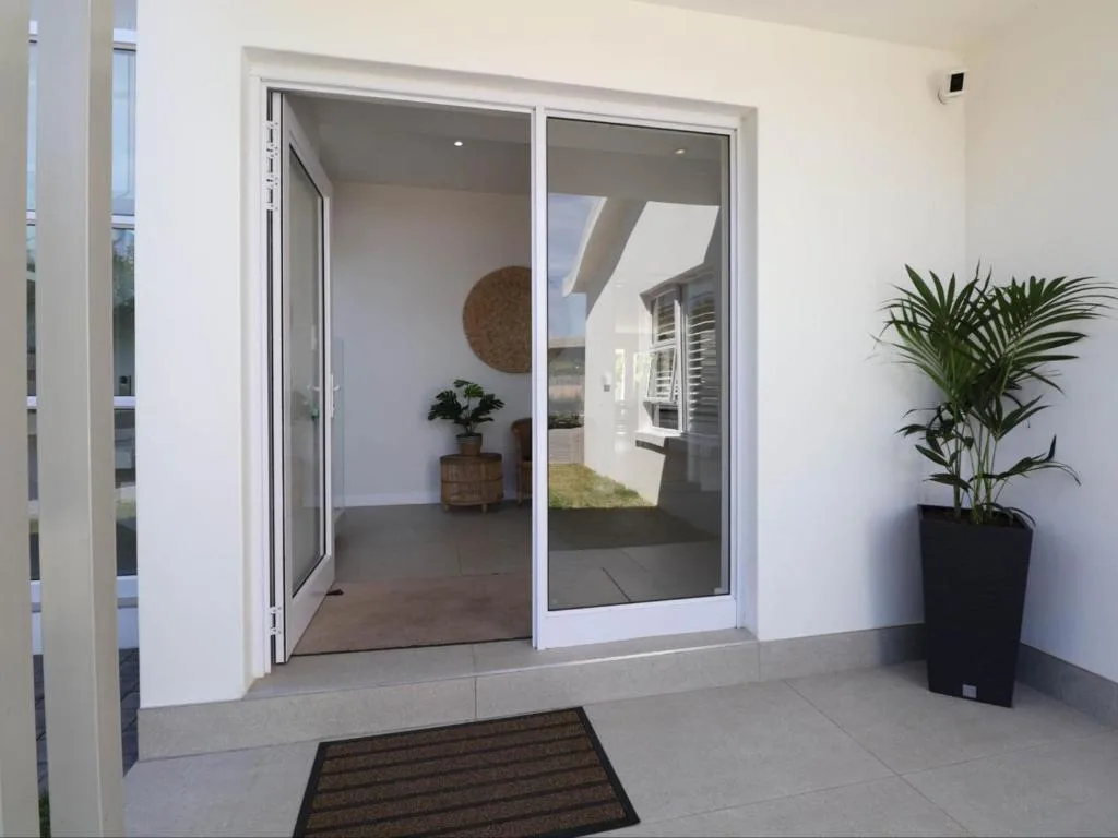 Modern white exterior with glass sliding doors and potted plant entrance