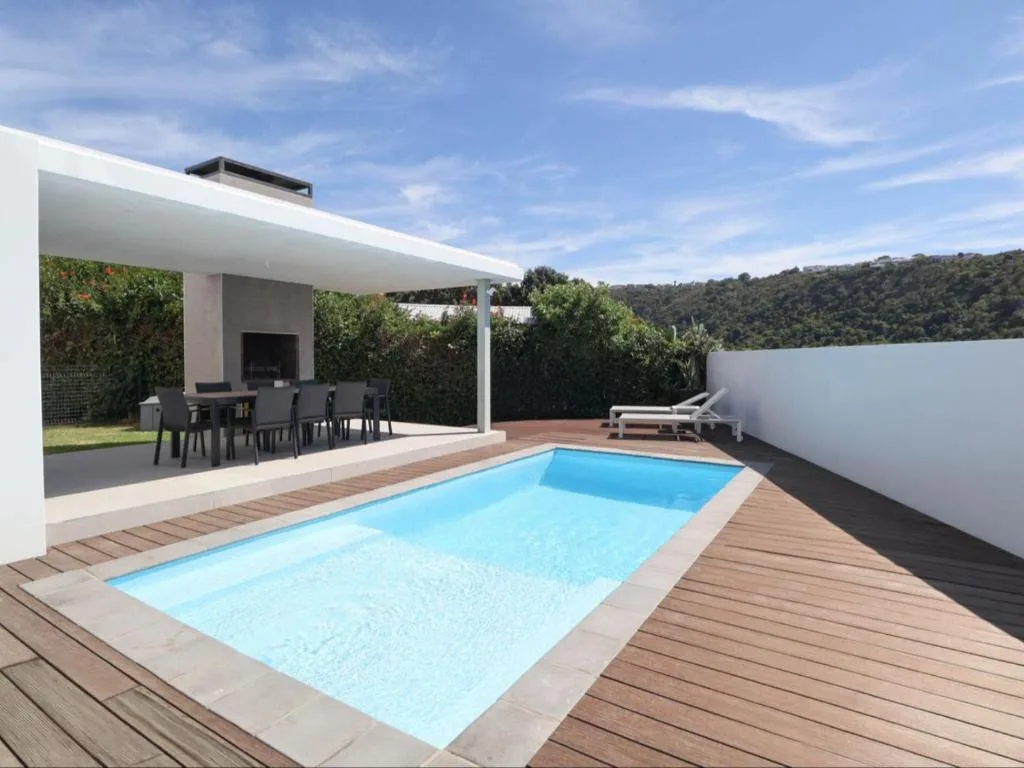 Modern swimming pool with wooden deck overlooking forested hills