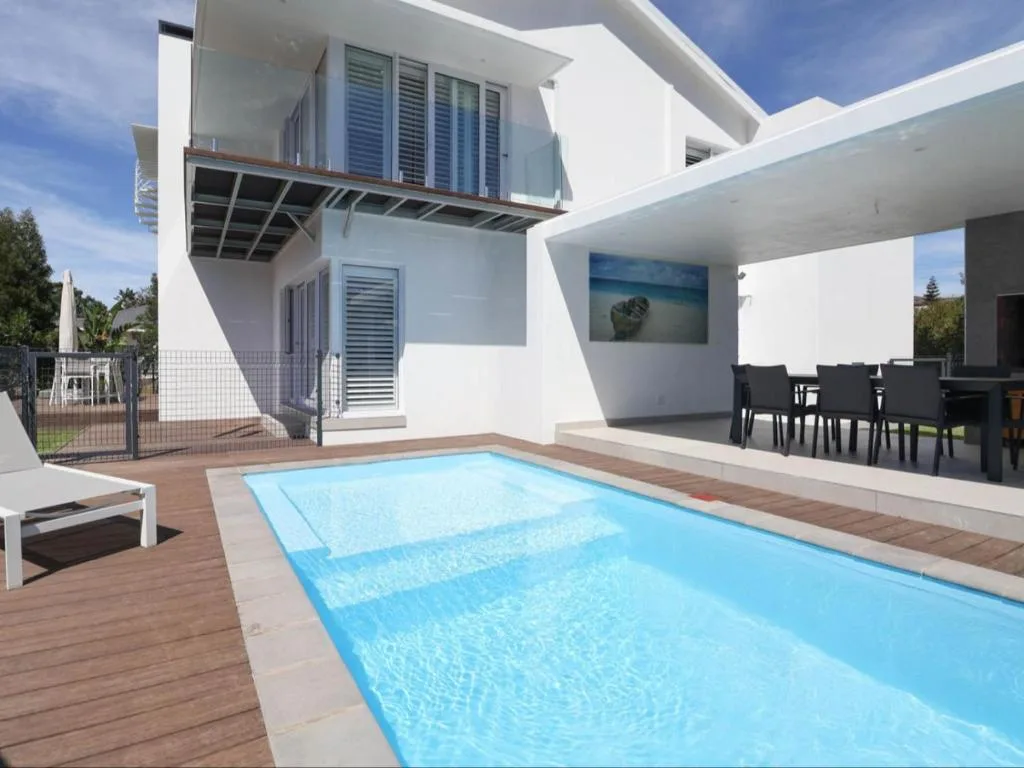 Sparkling swimming pool with modern white house and deck area