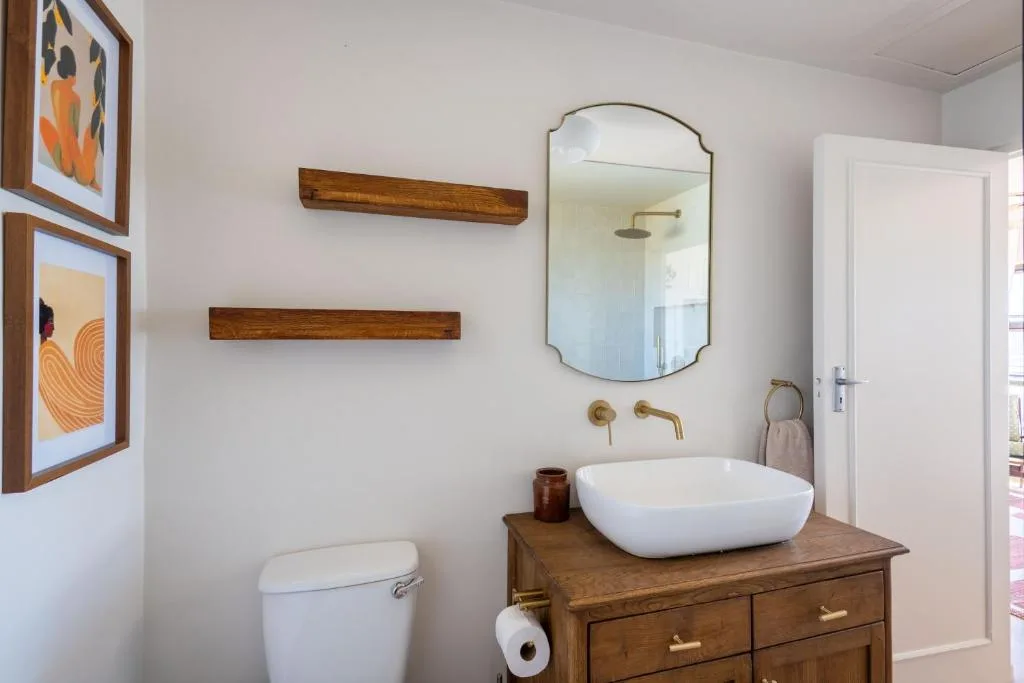 Modern bathroom with white vessel sink, wooden vanity, and framed artwork