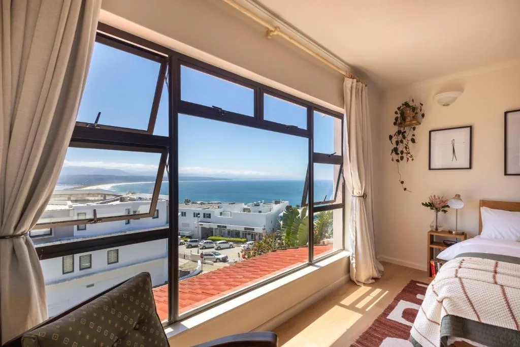 Bedroom with ocean view through large windows overlooking Plettenberg Bay coastline