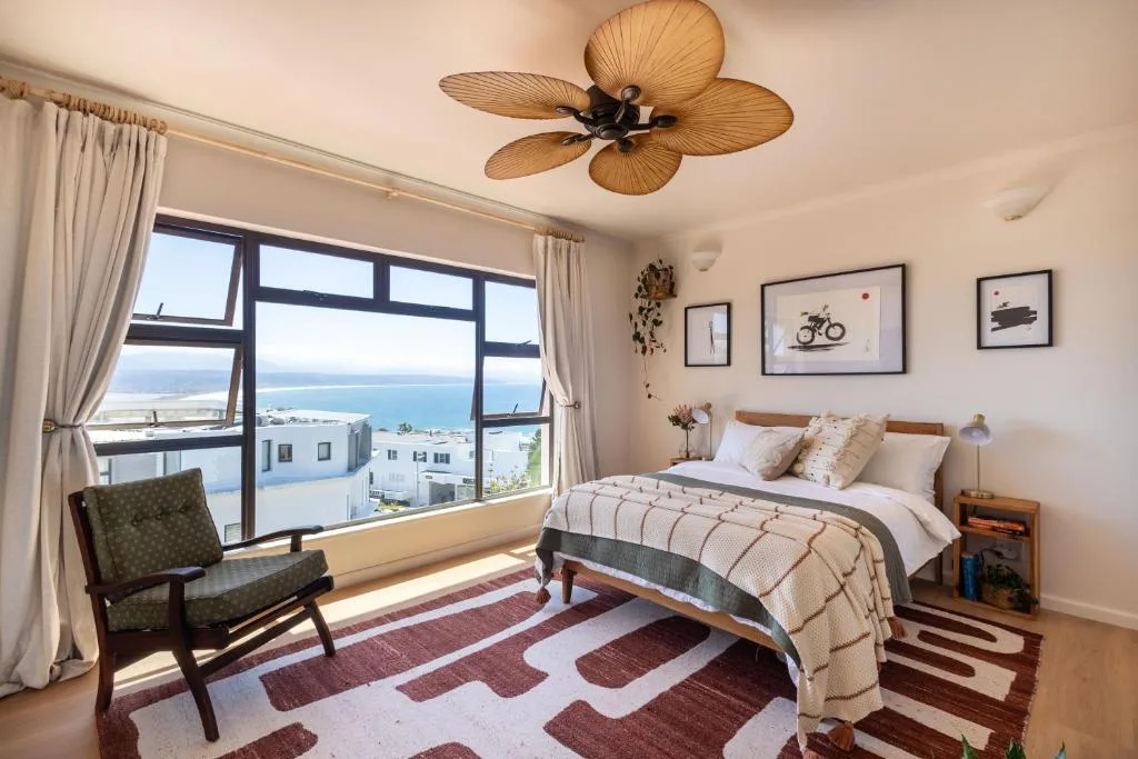 Bright bedroom with ocean view, wooden bed, and coastal decor elements