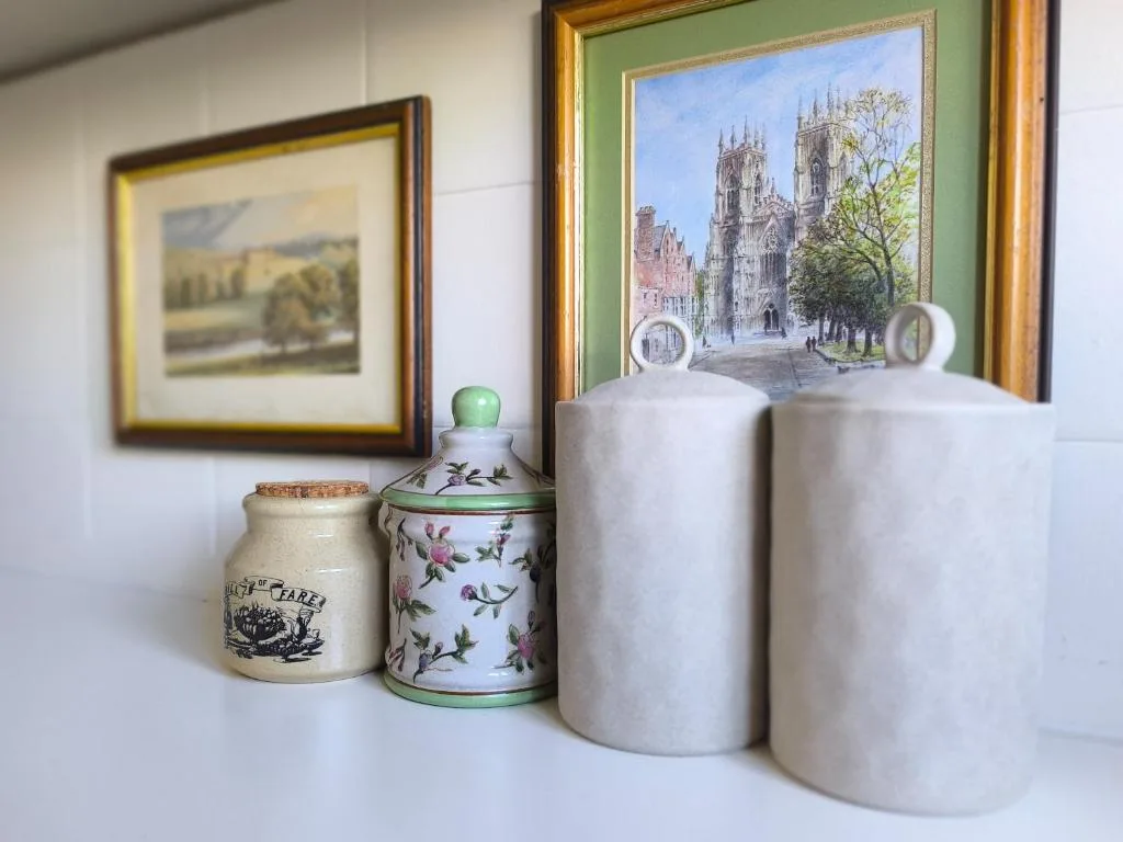 Decorative ceramic vessels and framed European architectural prints on shelf