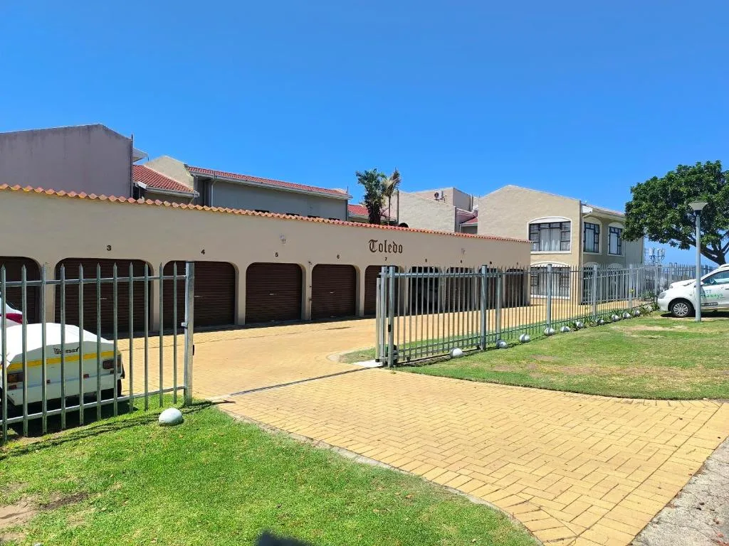 Modern apartment building with garages and manicured gardens under clear sky