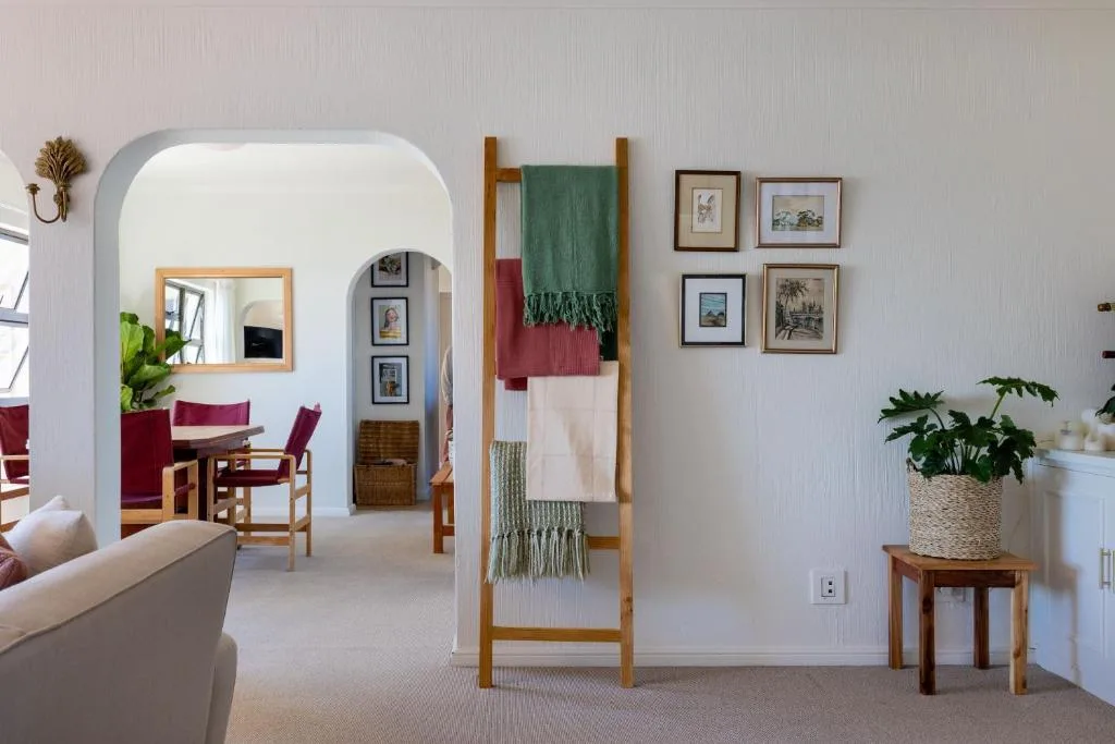 Spacious lounge with cream sofa, archway to dining area, blanket ladder, framed artwork
