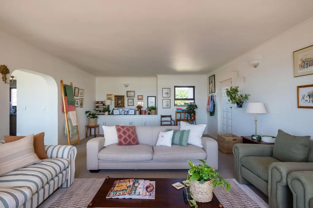 Bright living room with grey sofa, striped armchair, and green accent seating