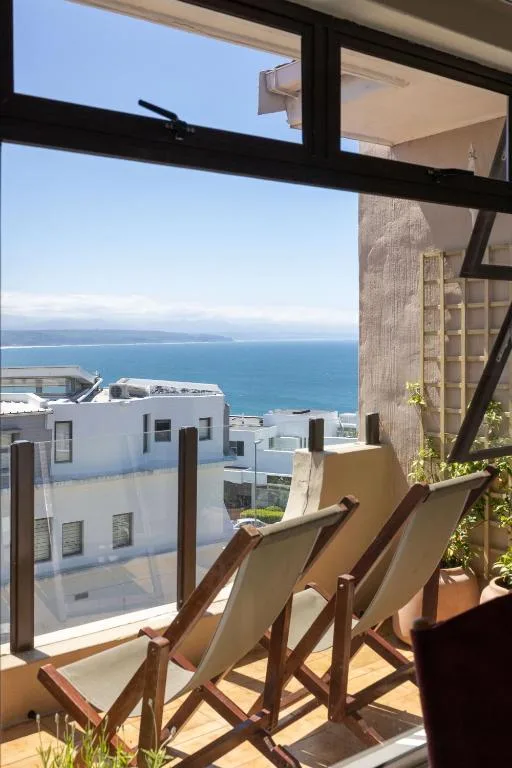 Ocean view from apartment deck with loungers and coastal town below