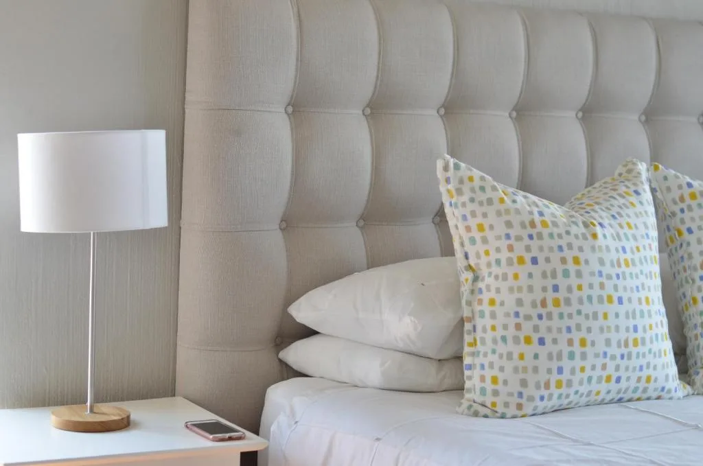 Modern bedroom with upholstered headboard, white pillows, and colorful accent cushions