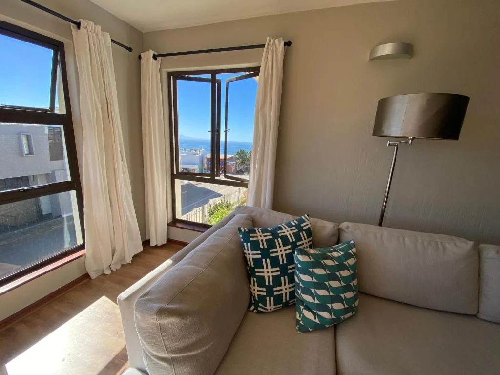 Spacious lounge with beige sofa, ocean view doors, and modern floor lamp