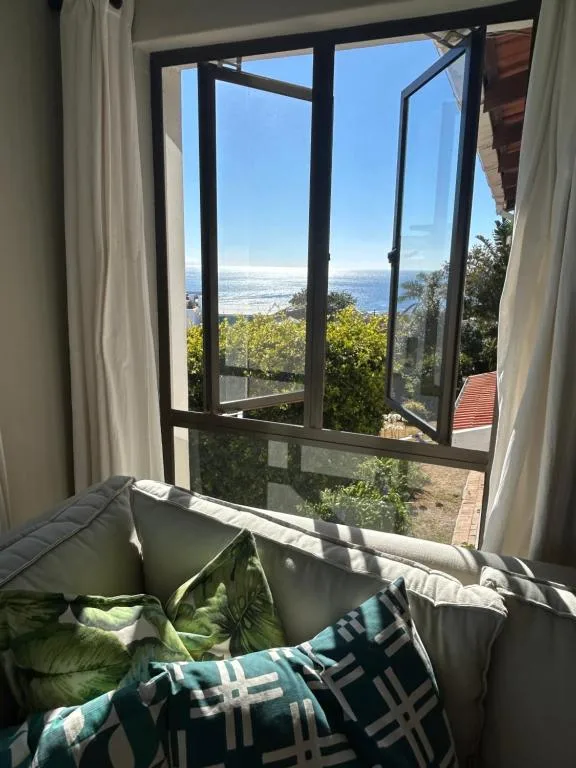 Expansive ocean and coastal landscape visible through open windows from bedroom