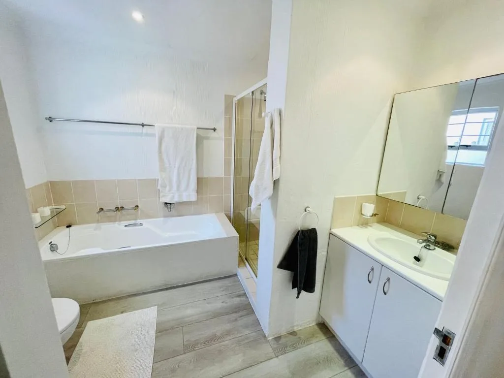 Clean modern bathroom with bathtub, shower enclosure, and dual vanity