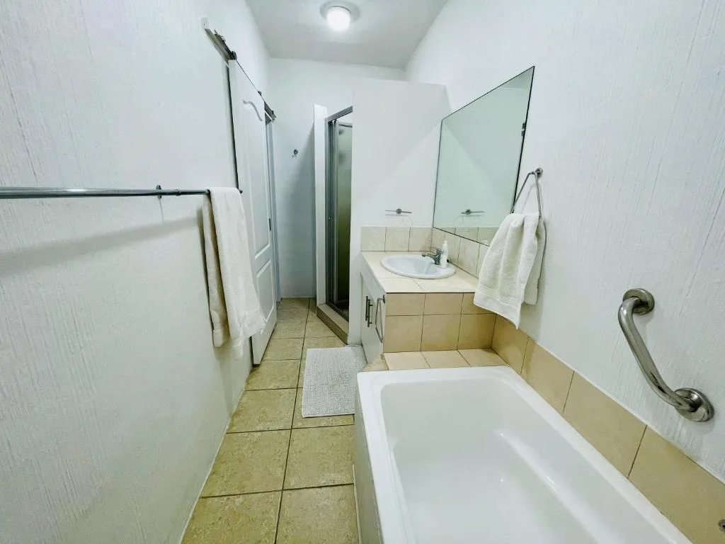 Clean bathroom with bathtub, sink vanity, and walk-in shower enclosure