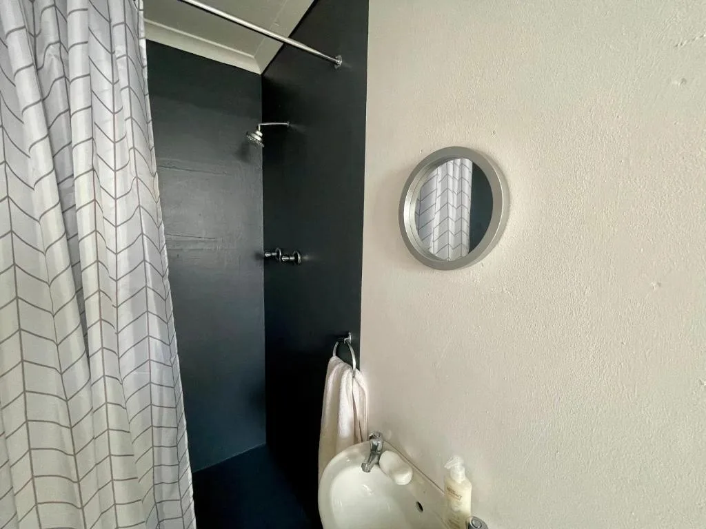 Modern bathroom with round mirror, pedestal sink, and black shower enclosure