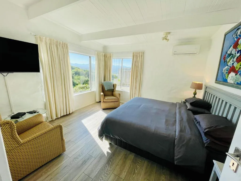 Spacious bedroom with queen bed, mountain views through large windows, and comfortable seating