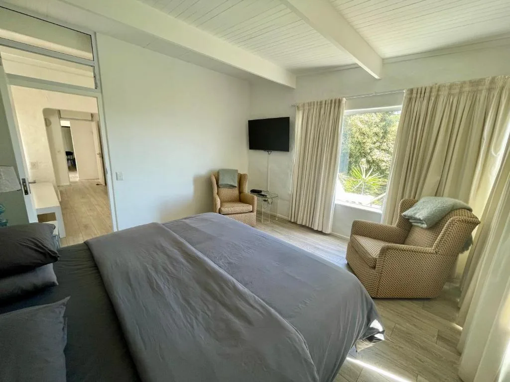 Spacious bedroom with queen bed, armchair, TV, and garden views