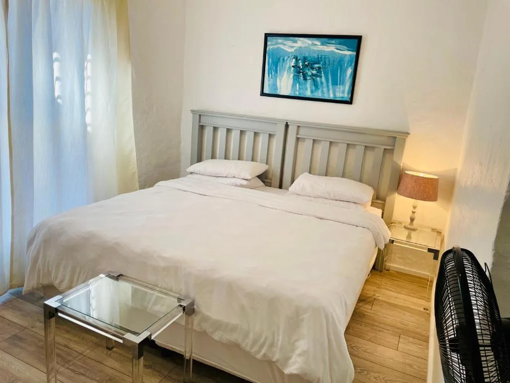 Spacious bedroom with double bed, cream headboard, and framed artwork