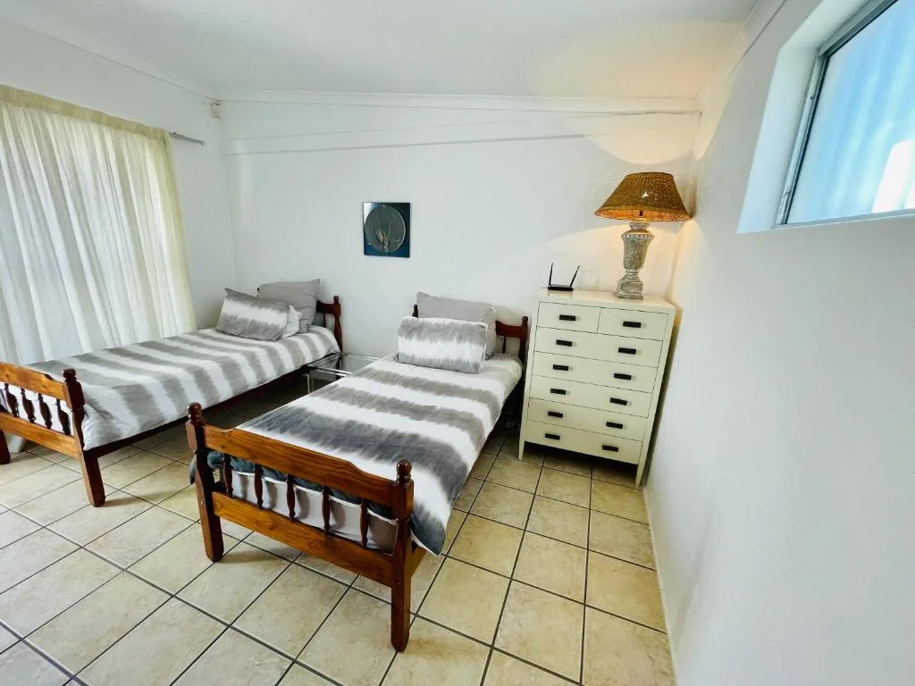 Bright bedroom with two wooden single beds and striped bedding