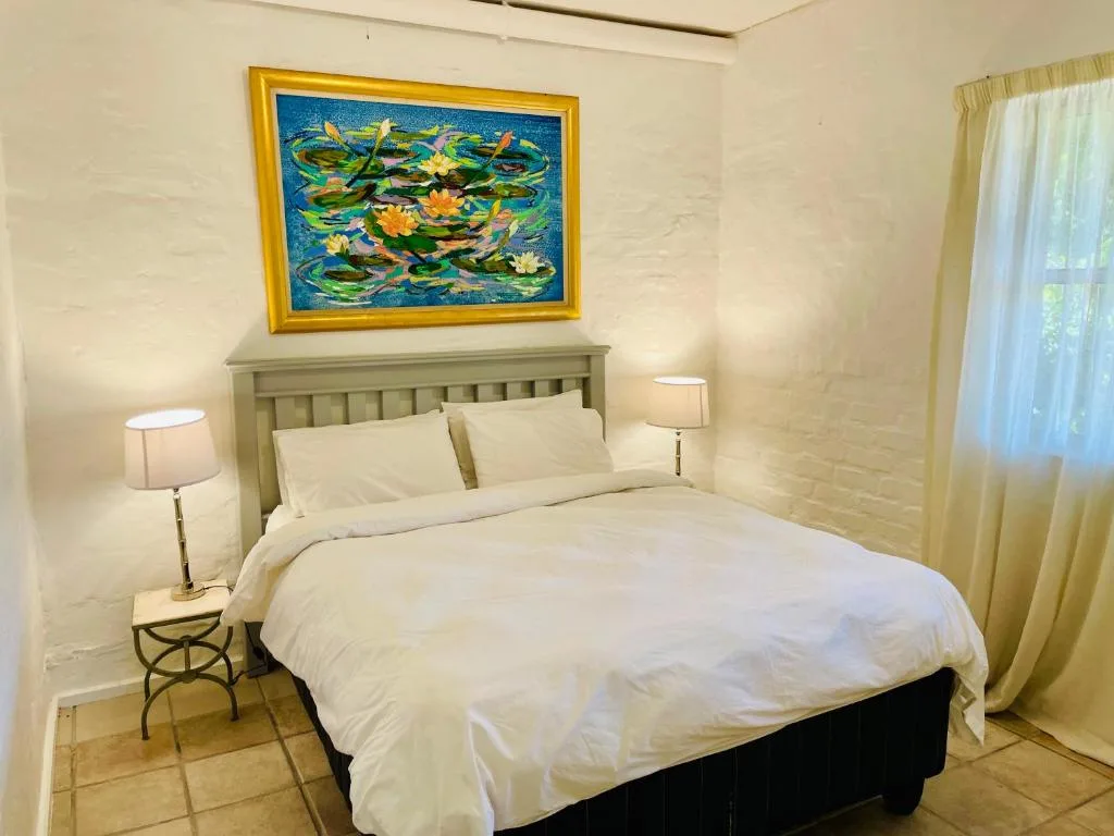 Bright bedroom with queen bed, sage headboard, white linens, and lily pad artwork