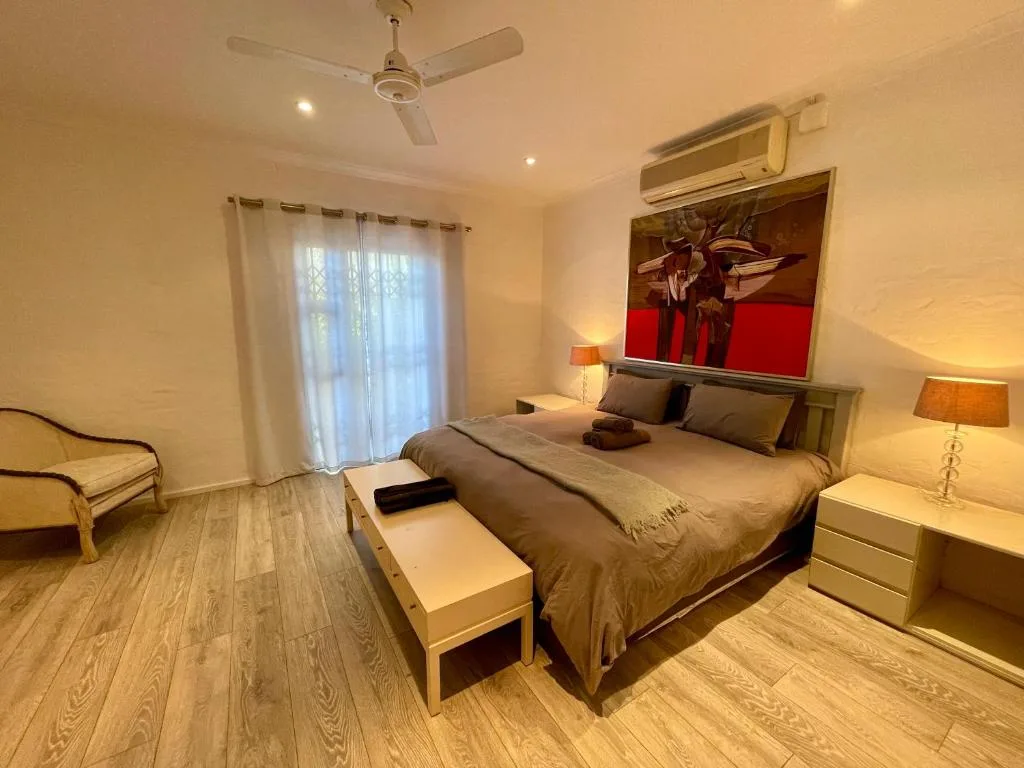 Spacious bedroom with queen bed, modern furnishings, and garden access doors