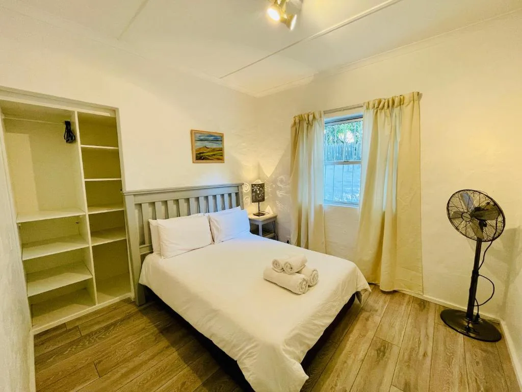 Bright bedroom with queen bed, white linens, and open wardrobe storage