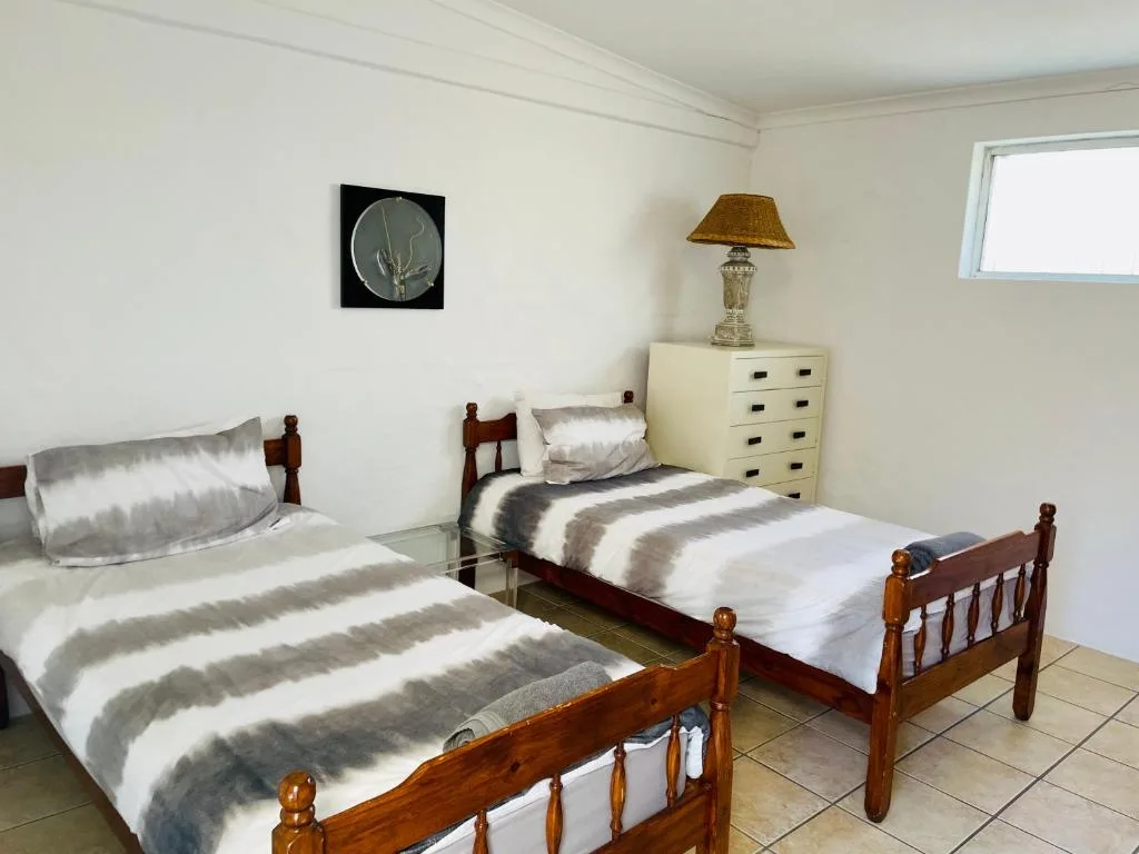 Twin bedroom with striped bedding, wooden beds, cream dresser, and wall art